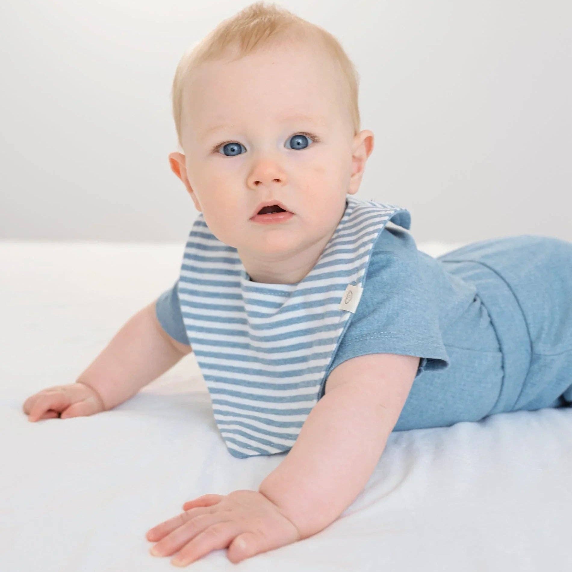 Baby wearing a blue and white striped outfit on a white background