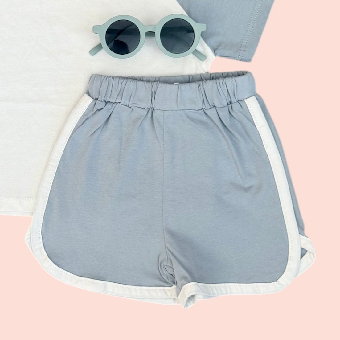 Light blue shorts with white trim on a pink background