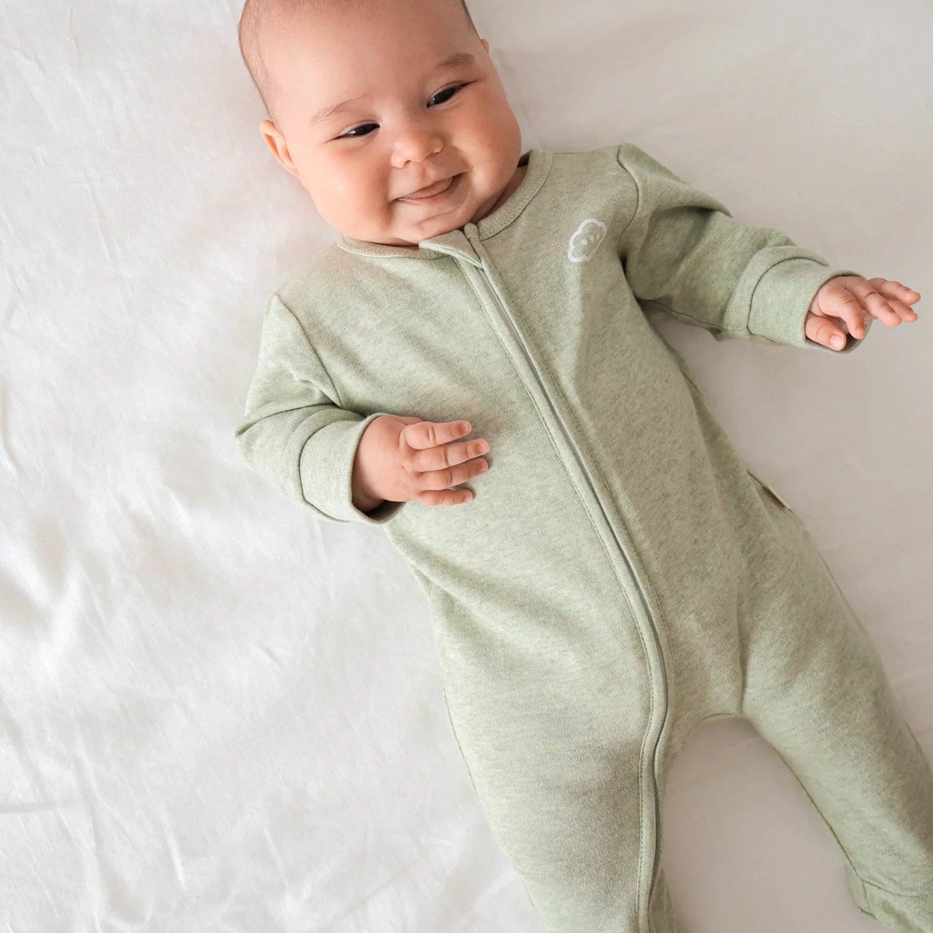 Baby wearing a green onesie on a white background