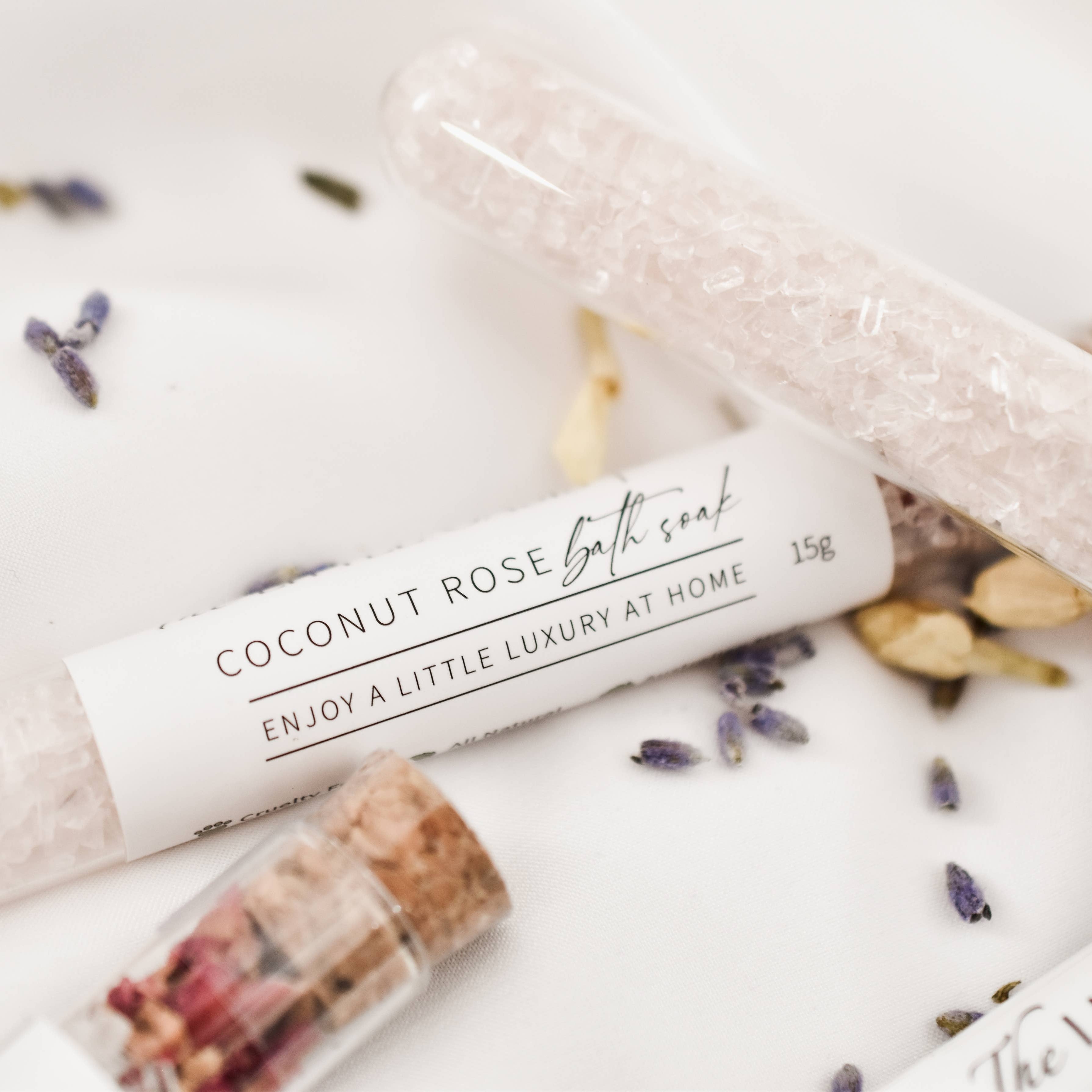 Coconut Rose bath soap with packaging on a white surface with lavender and rose petals.