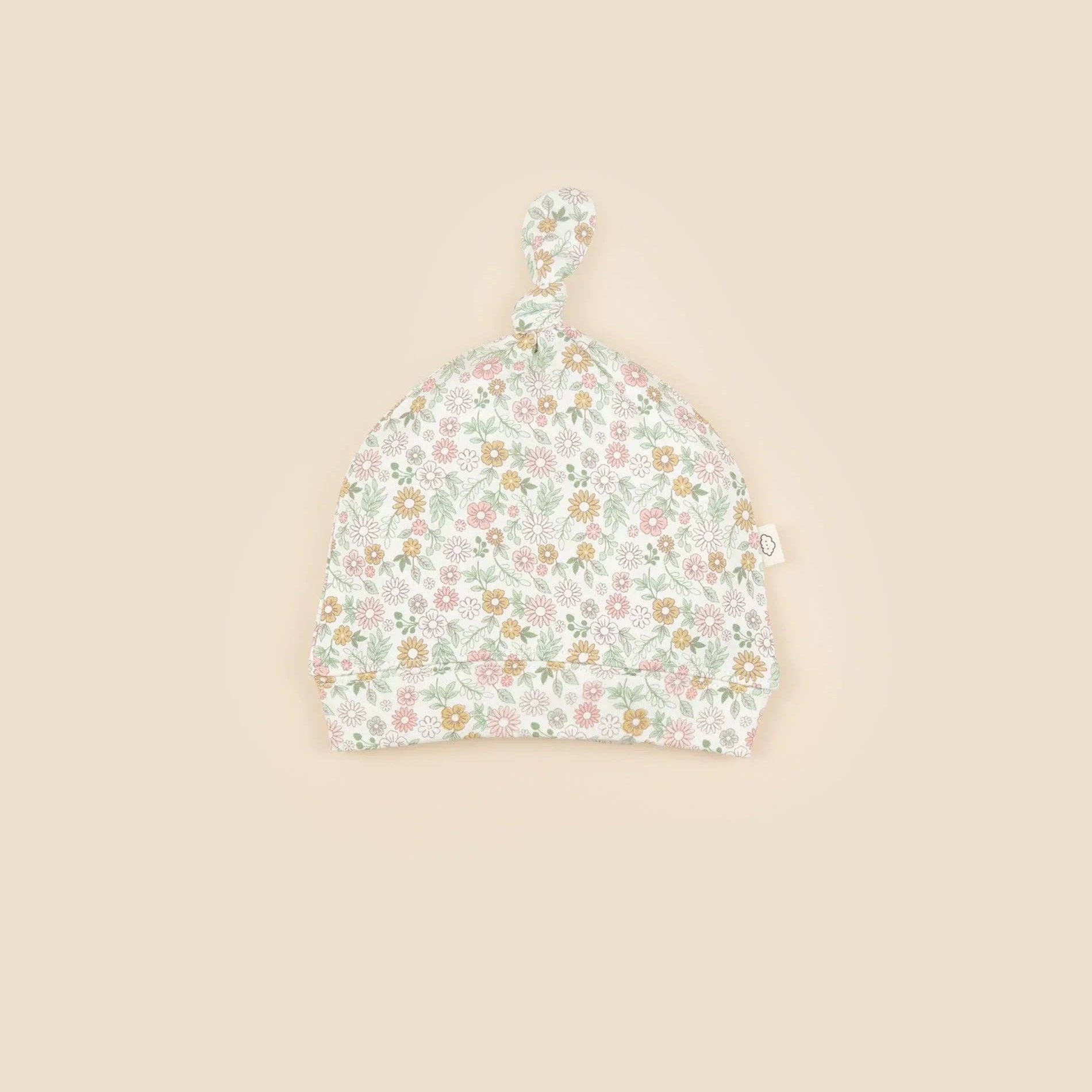 Floral patterned baby hat on a beige background