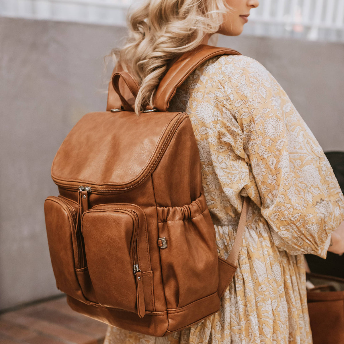 Woman wearing a brown leather backpack indoors