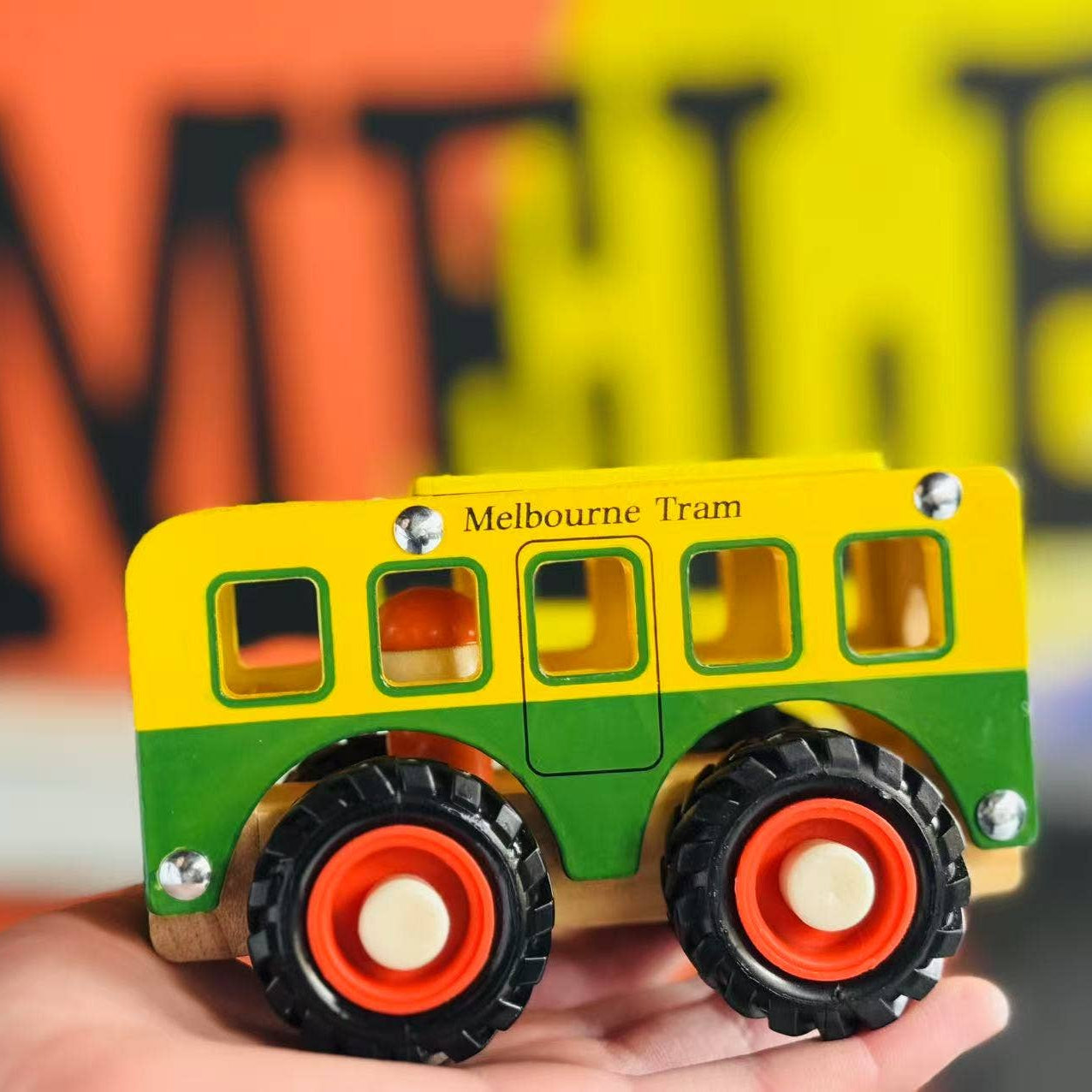 Toy Melbourne tram model held in a hand with blurred background